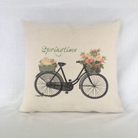 Pillow with sublimated black bike filled with spring flowers in the basket. Image purchased thr